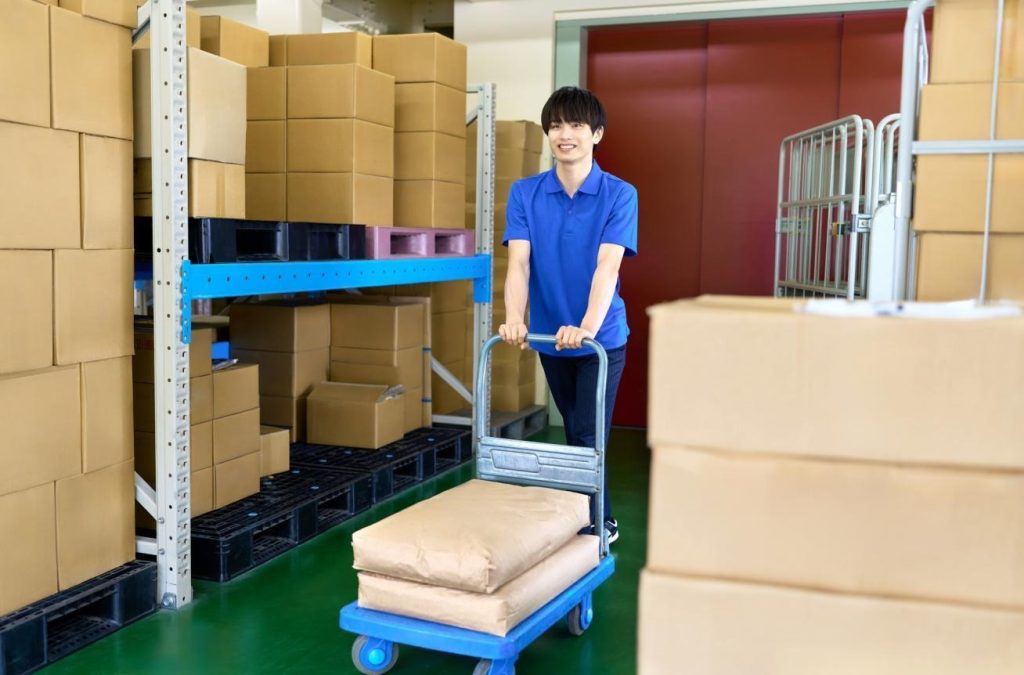 倉庫で運搬台車を使い、重量物を運ぶ人